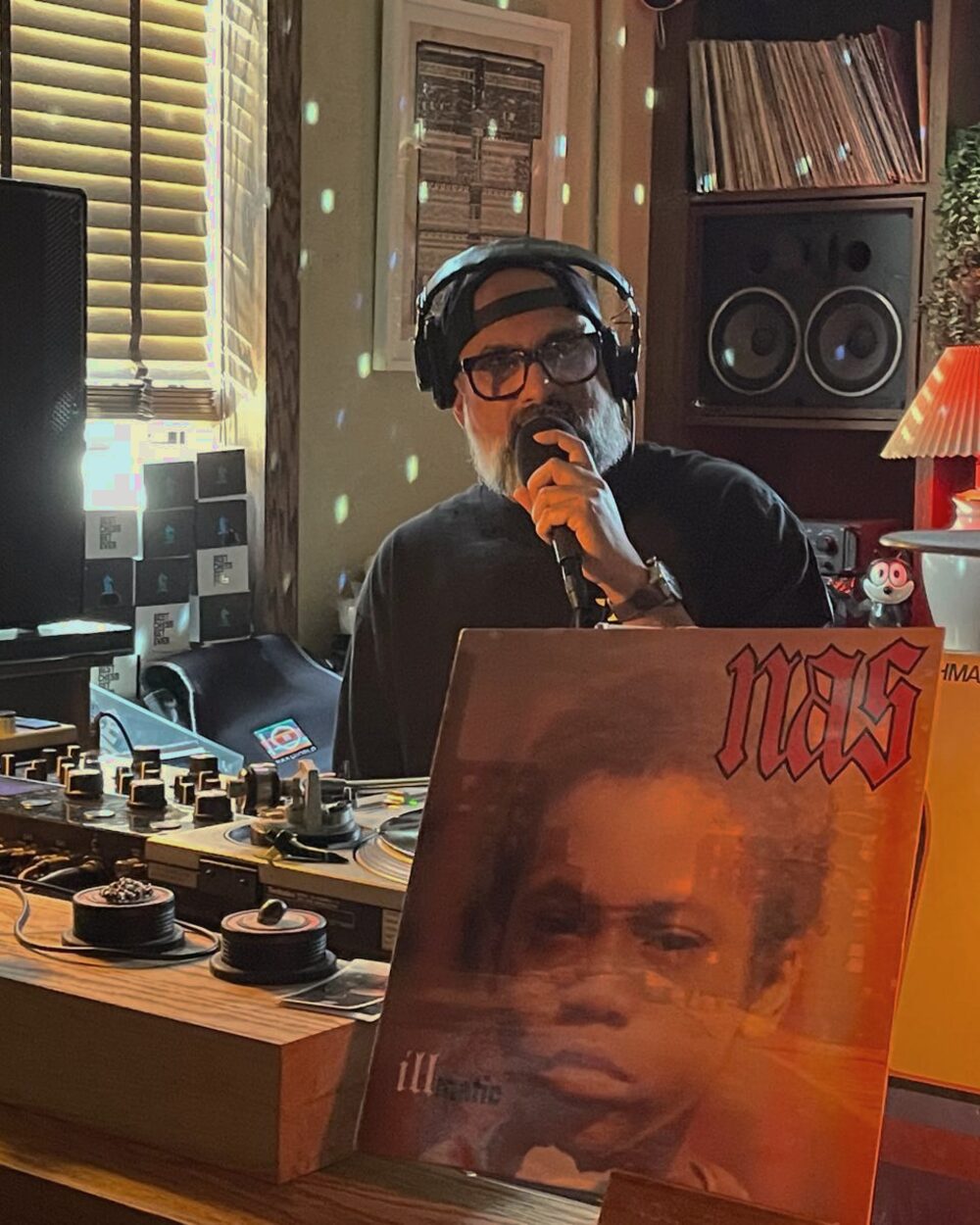 Steven on the mic introducing a record, Illmatic on display beside the decks